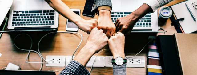 Team members put fists together in a circle