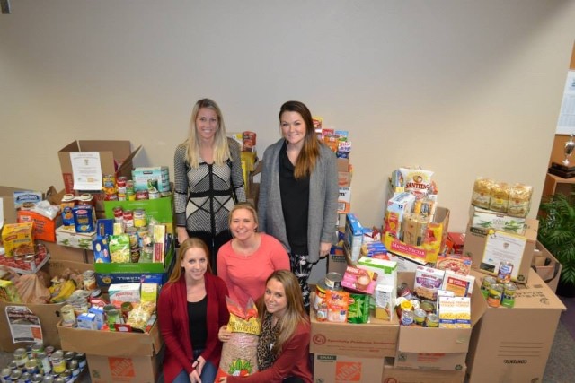 Women standing among the food they collected for a food drive